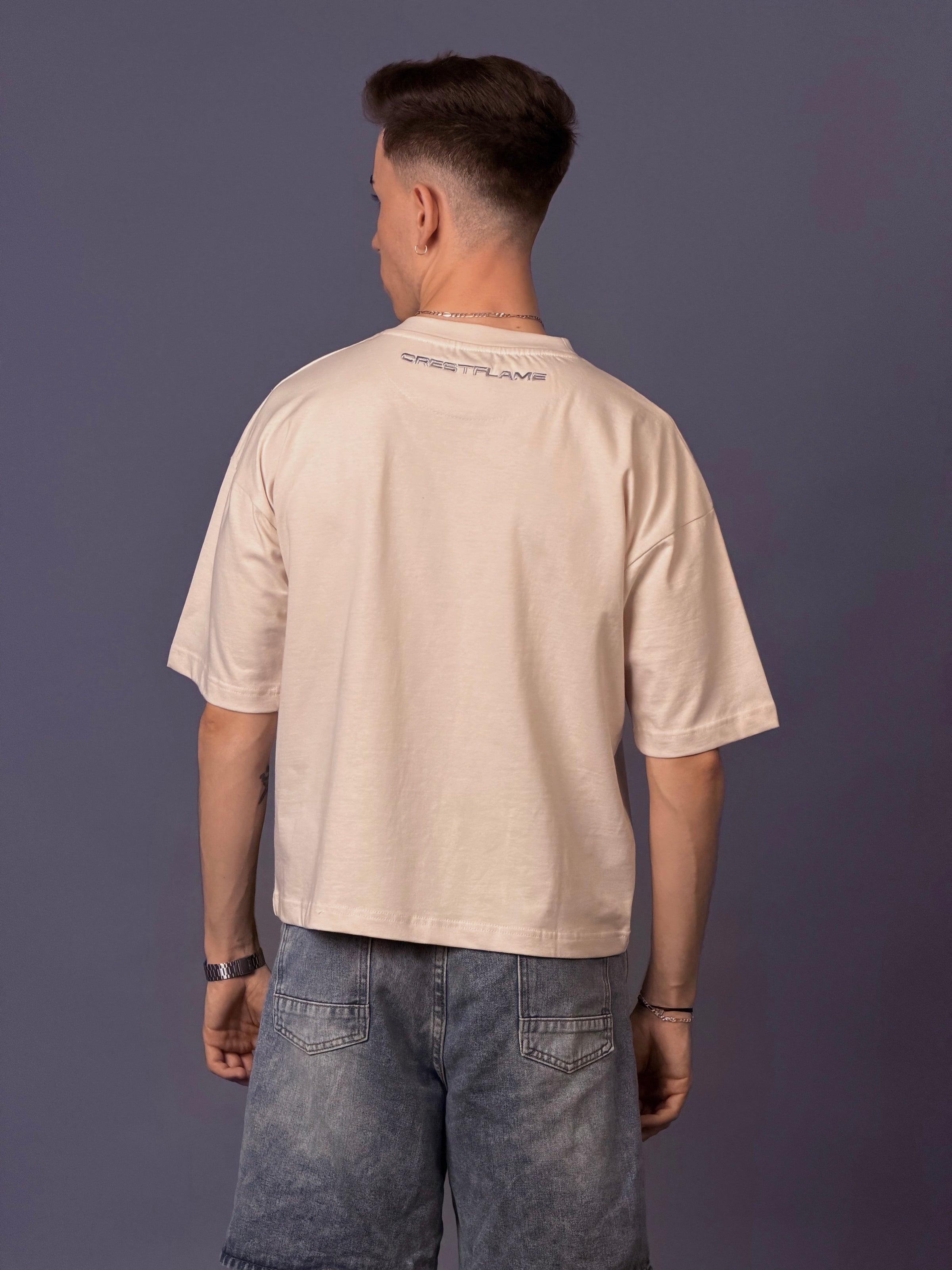 Man wearing a beige t-shirt with text on the back against a purple background
