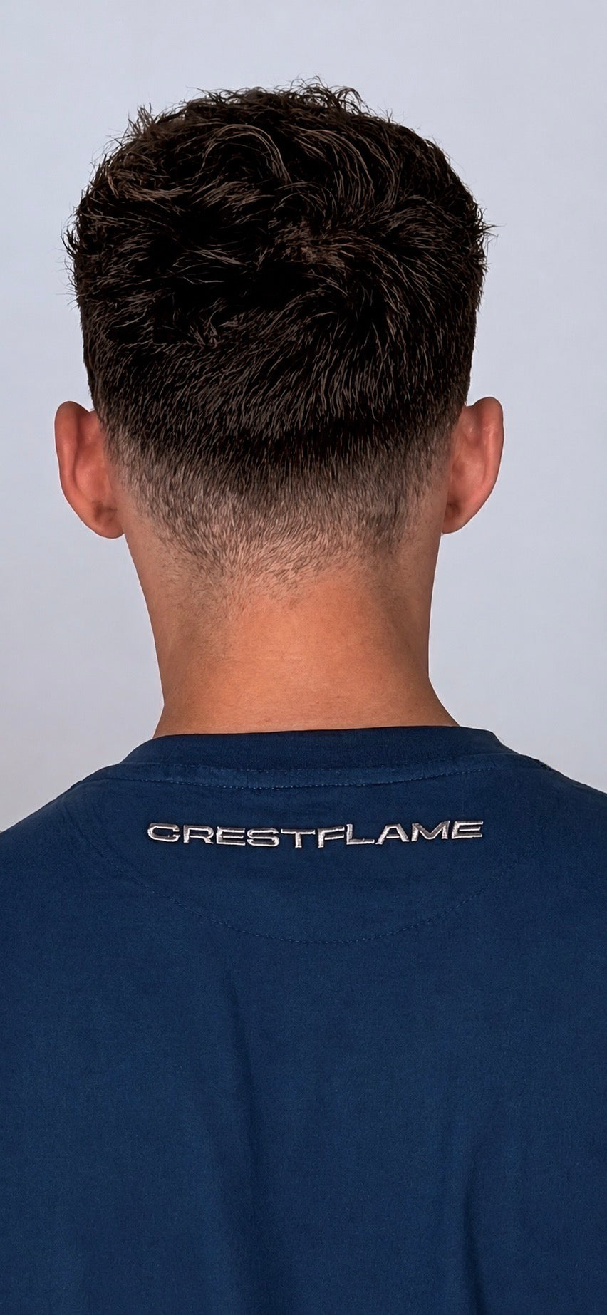 Person wearing a blue t-shirt with 'CRESTFLAME' logo on the back against a gray background