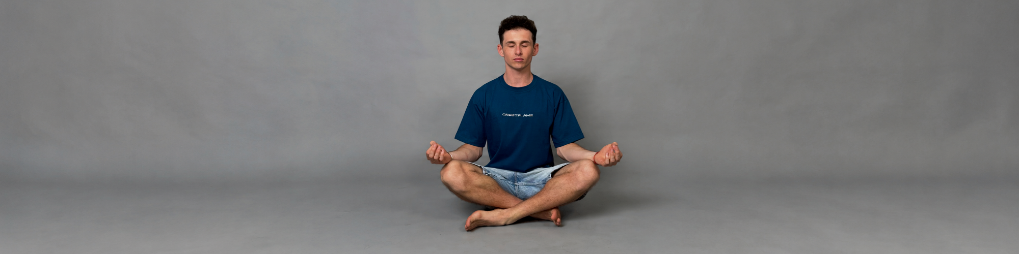 Person sitting in a meditative pose on a gray background
