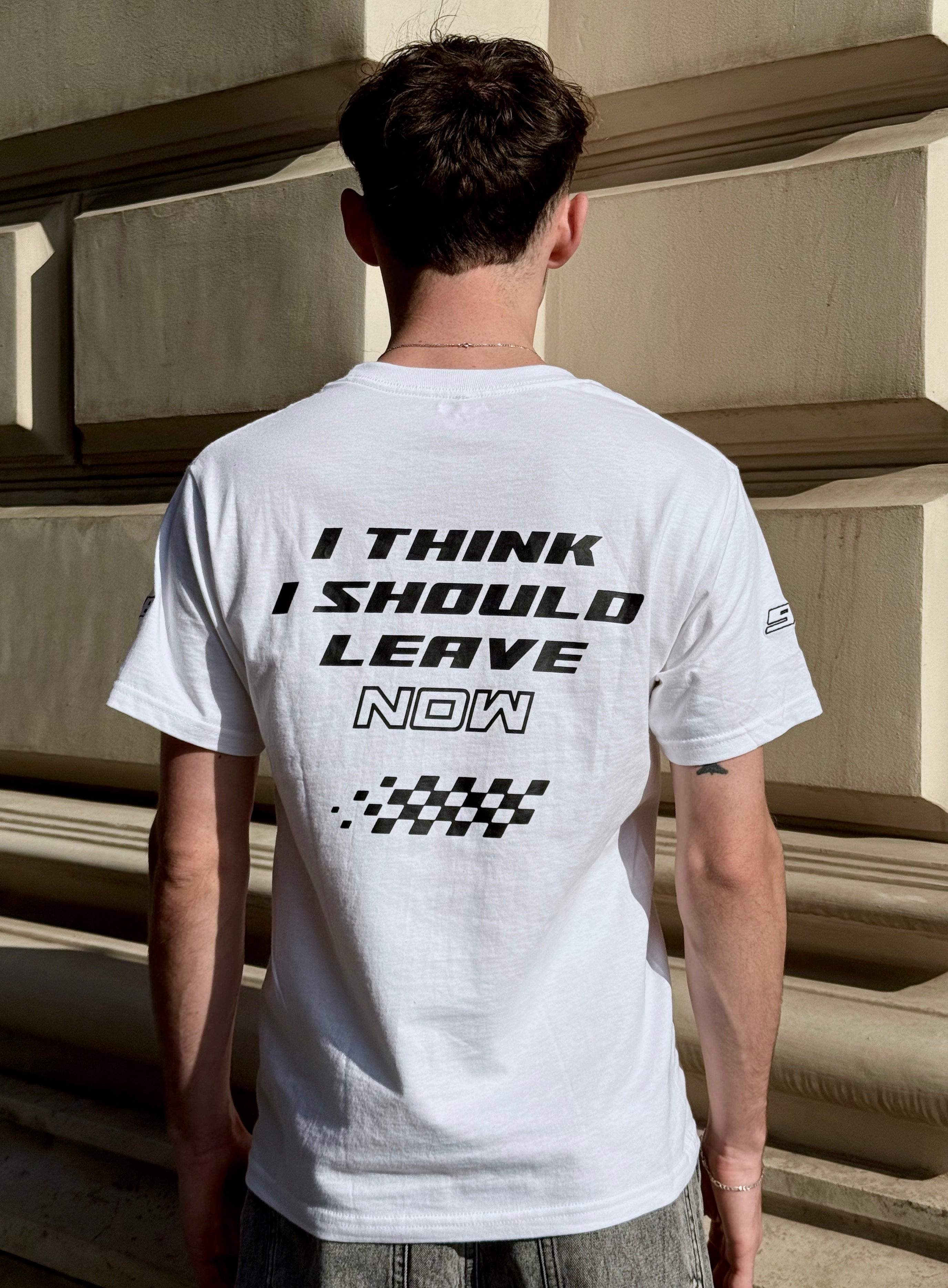 Person wearing a white t-shirt with text on the back, standing on steps.