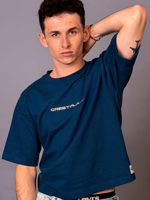 Man wearing a blue t-shirt with 'Crestflash' logo against a gray background